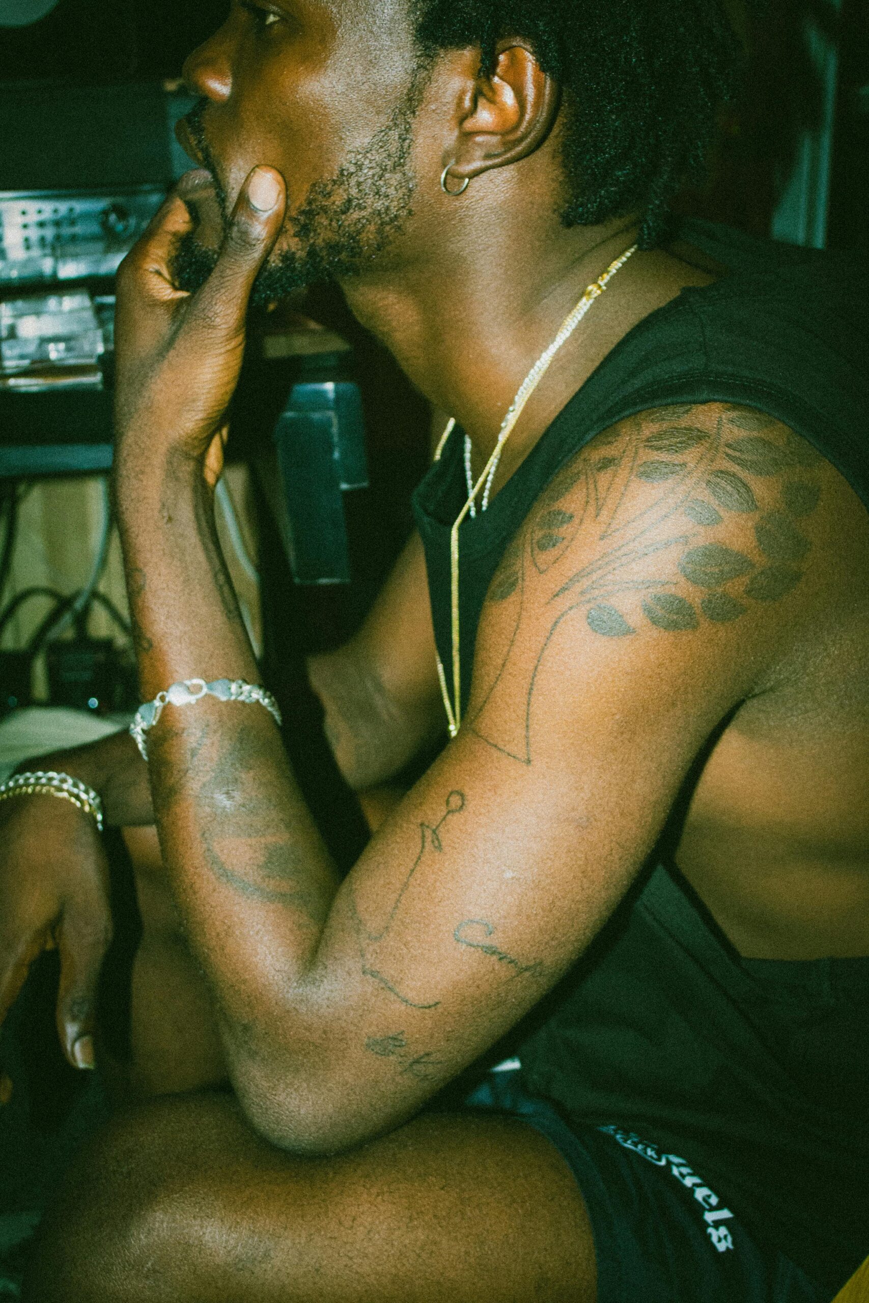 African man with tattoos in profile view, seated thoughtfully in Accra, Ghana.